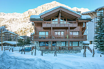 A large wooden house with a mountain in the background