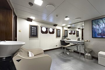 A room with a chair a sink and a mirror
