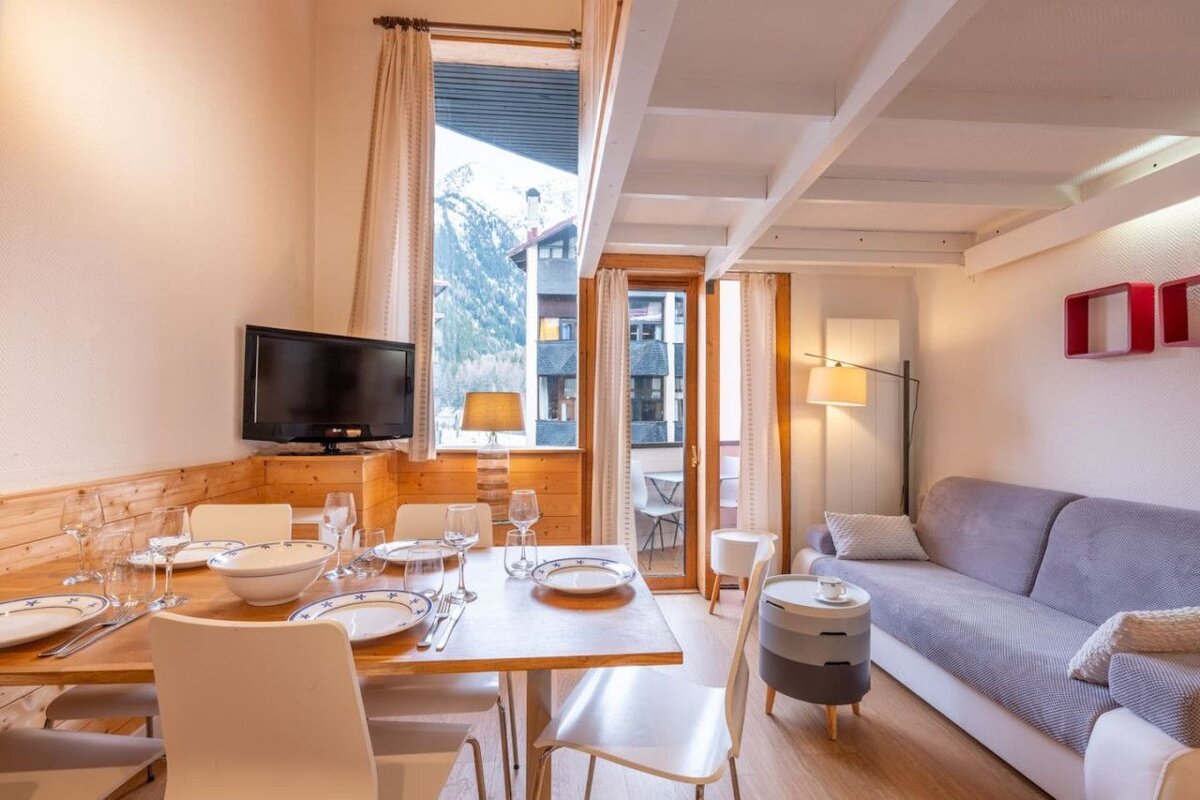 A living room with a table and chairs and a flat screen tv