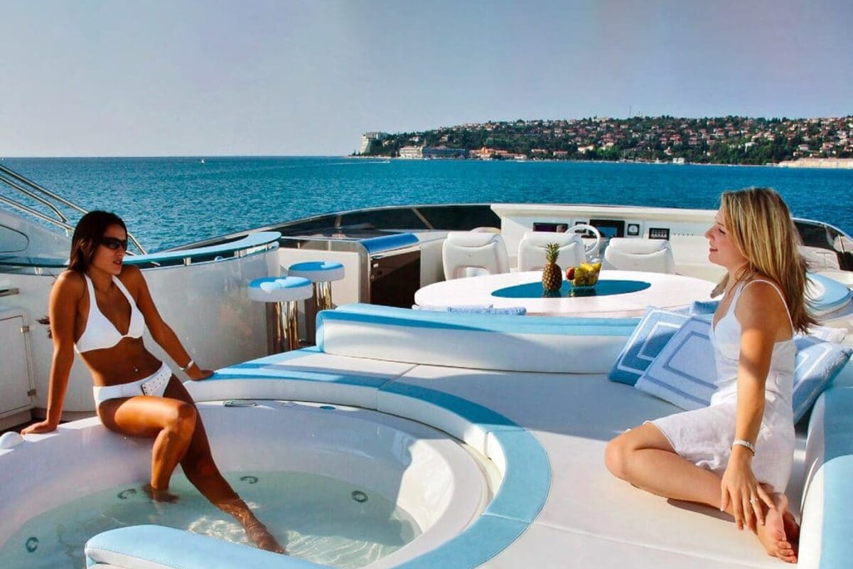 Two women sit in a jacuzzi on the deck of a boat