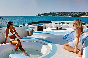 Two women sit in a jacuzzi on the deck of a boat