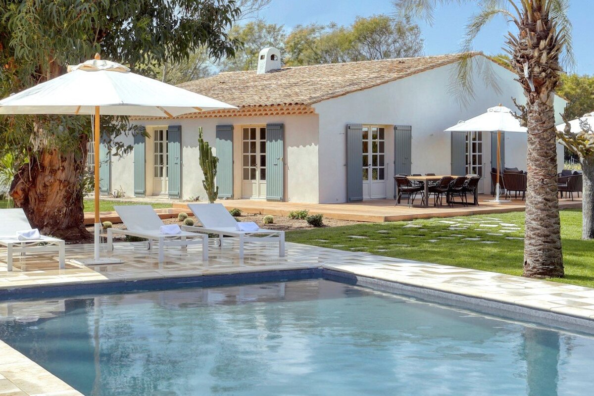 A white house with a swimming pool in front of it