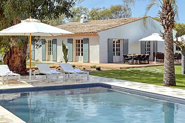 A white house with a swimming pool in front of it