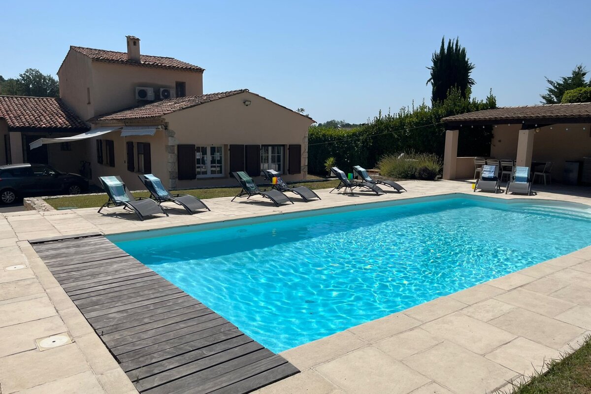 A swimming pool with chairs around it and a house in the background