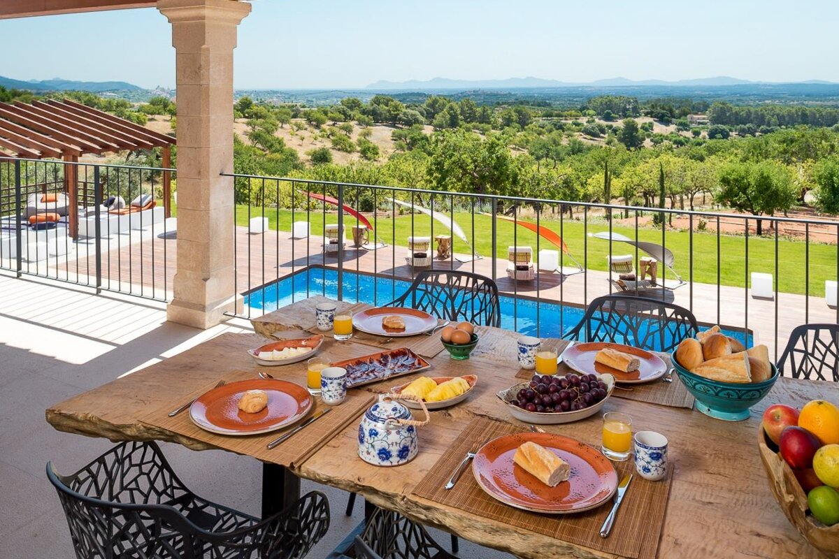 A table with plates of food on it with a view of a swimming pool