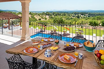 A table with plates of food on it with a view of a swimming pool