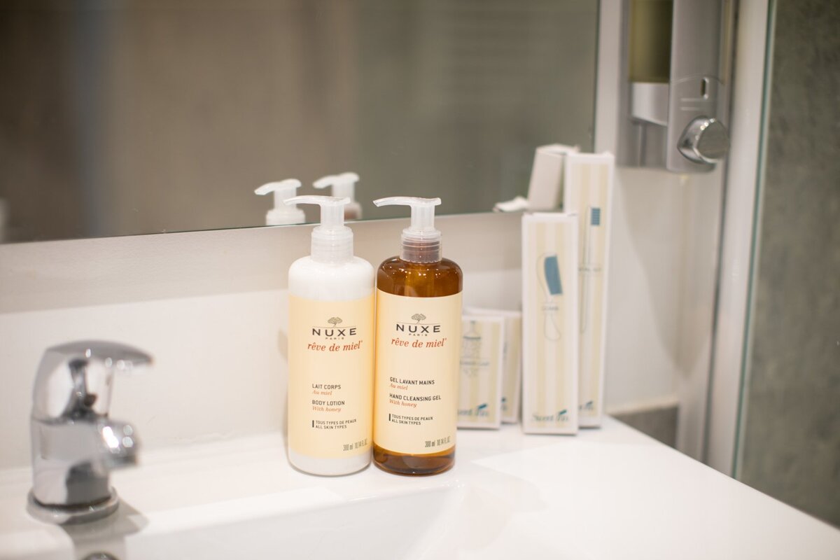 Two bottles of nuxe sit on a bathroom sink