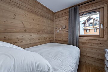 A bedroom with wooden walls and a white bed