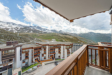 A balcony with a view of the mountains and a building that says ' hotel ' on it