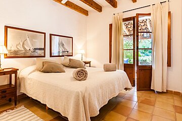 A bedroom with a bed and two paintings of sailboats on the wall