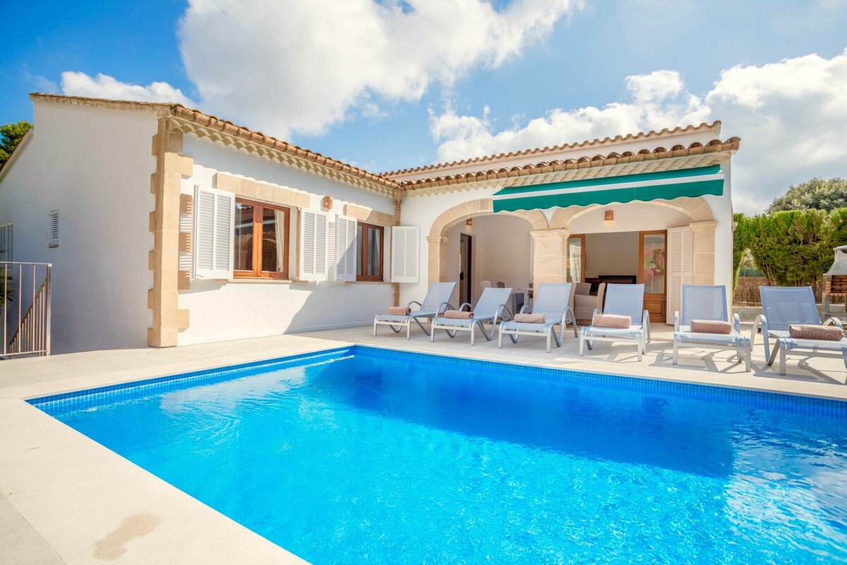 A white house with a swimming pool in front of it