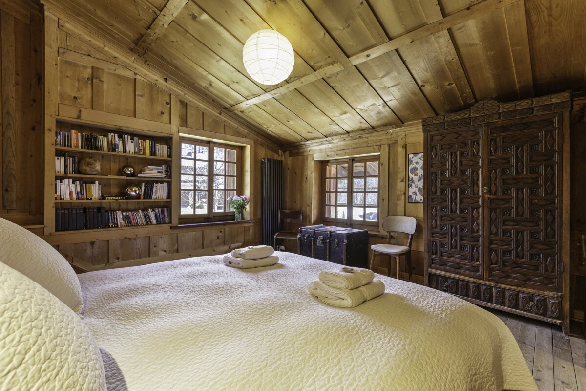 A bedroom with a bed and a bookshelf with books on it