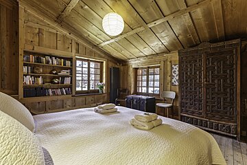 A bedroom with a bed and a bookshelf with books on it