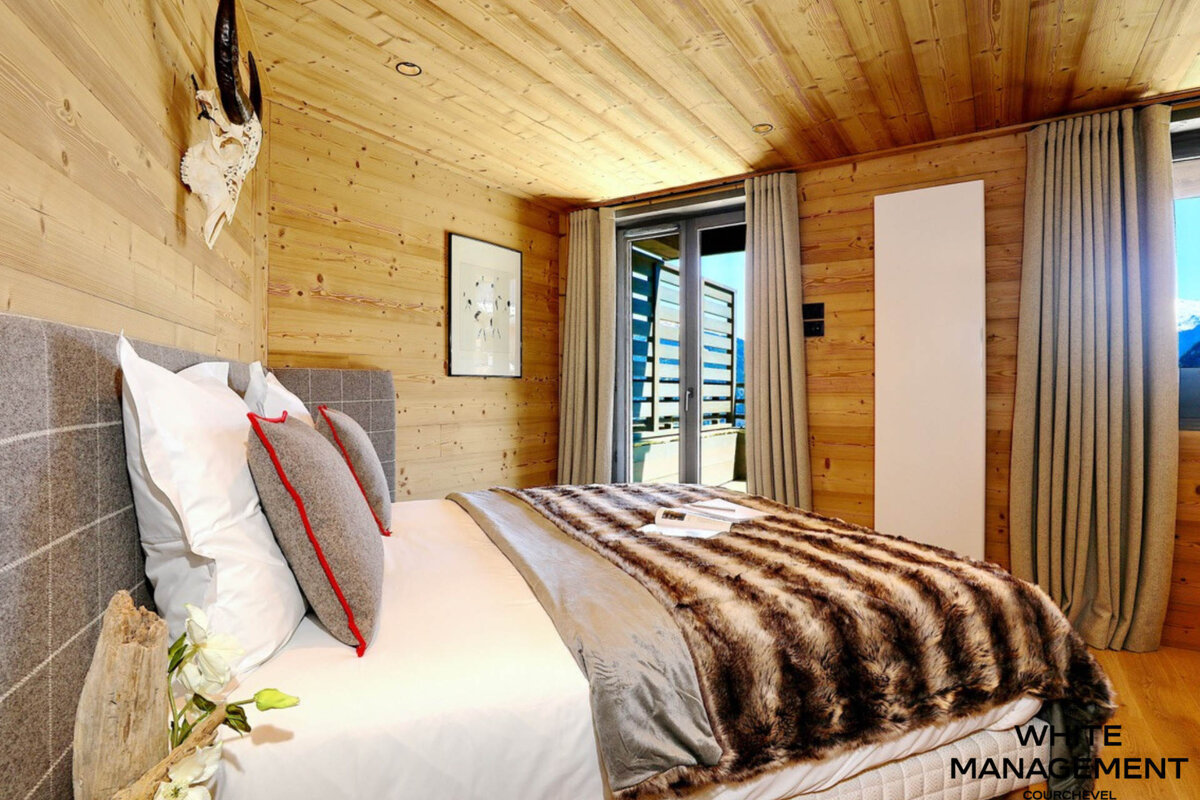 A bedroom with a rental designer logo on the corner