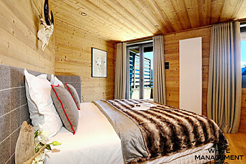 A bedroom with a rental designer logo on the corner