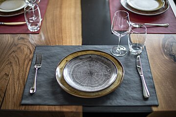 A place setting with plates glasses and silverware on a wooden table