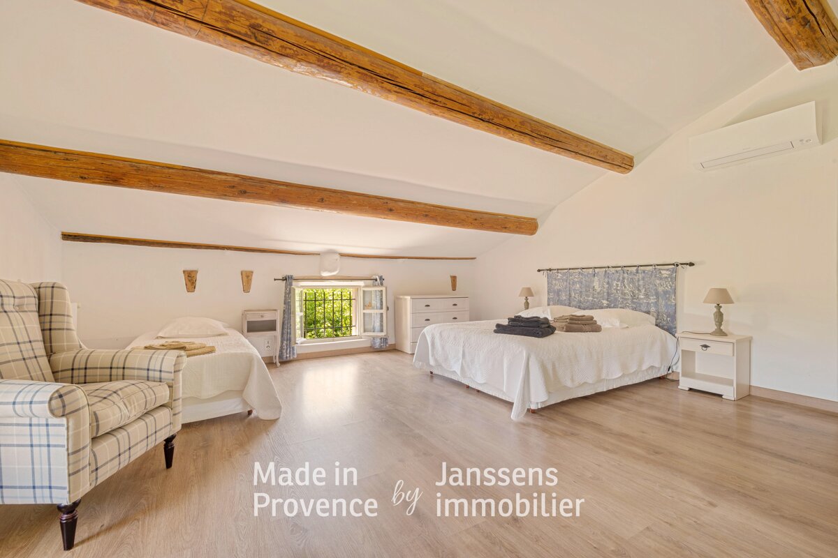 A bedroom with two beds and a chair made in provence by janssens immobilier