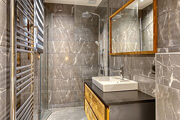 A bathroom with marble tiles and a sink and mirror