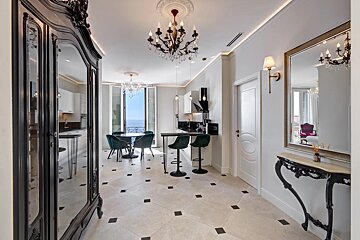 An opulent living space with a kitchen, dining area, chandeliers, and baroque furniture, offering a beautiful sea view.