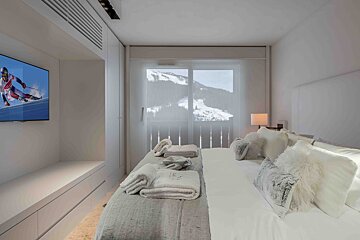 A bedroom with a large bed and a flat screen tv