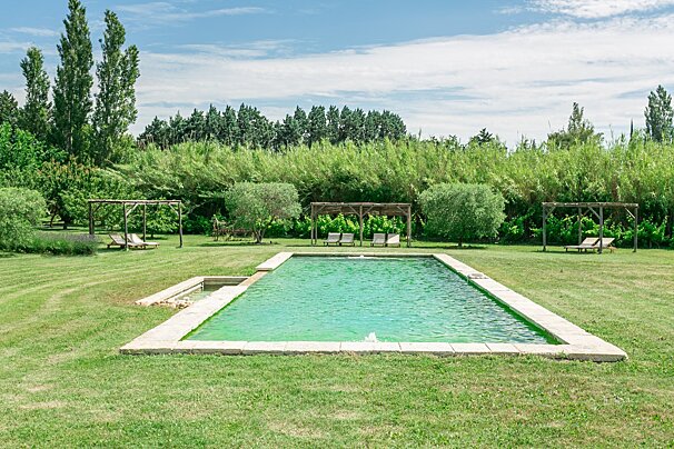 A large swimming pool in the middle of a lush green field