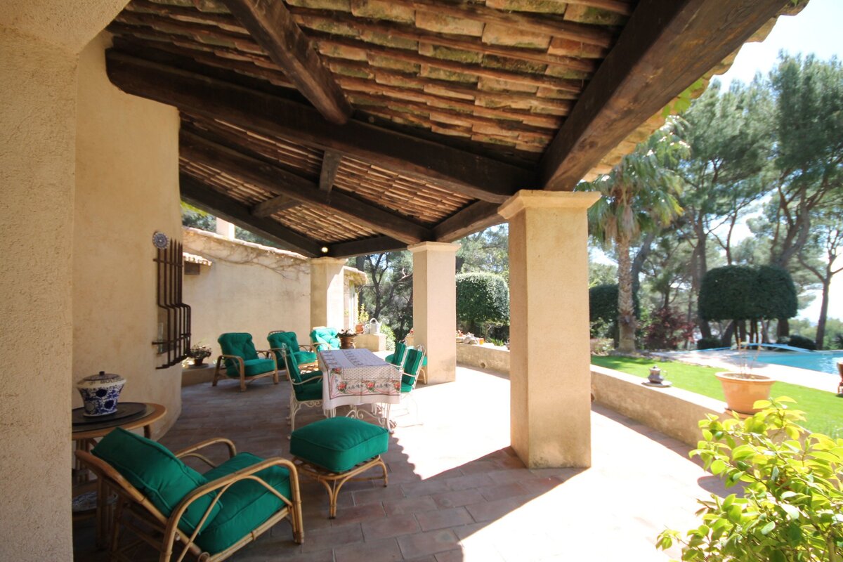 A patio with a table and chairs under a wooden roof