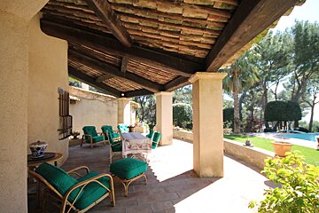 A patio with a table and chairs under a wooden roof