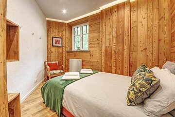 A bedroom with wood paneled walls and a bed