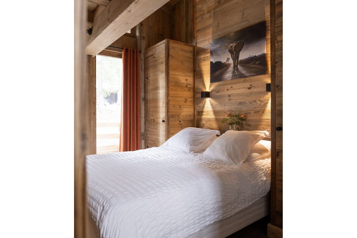 A bedroom with a painting on the wall above the bed