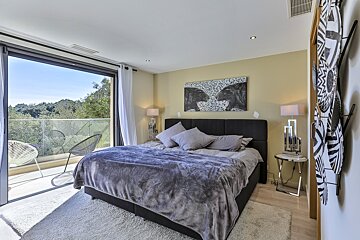 A bedroom with a large bed and a painting on the wall