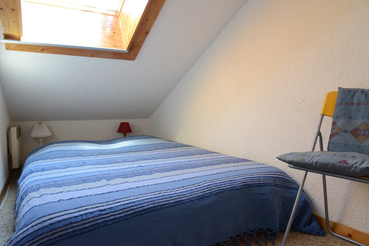 A small bedroom with a bed and a chair