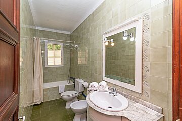 A bathroom with green tiles and a toilet and sink