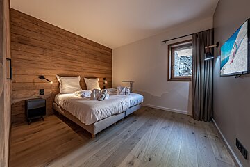 A bedroom with a large bed and a flat screen tv