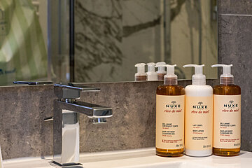 Three bottles of nuxe are on a bathroom counter