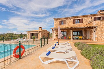 A large stone house with a swimming pool in front of it