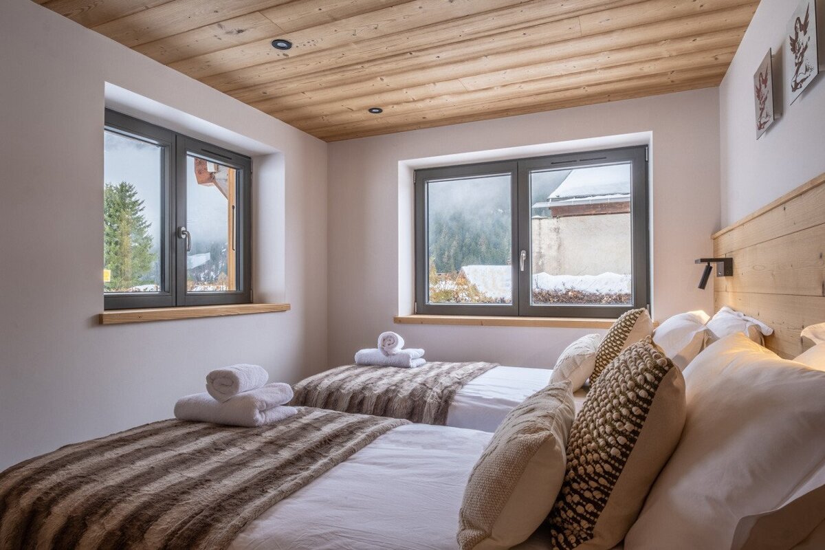 A bedroom with two beds and a large window