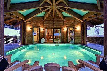 A large swimming pool is surrounded by wooden chairs