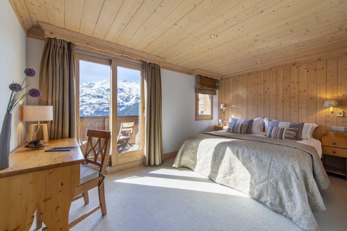 A bedroom with a bed and a desk with a view of the mountains