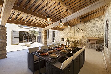 A dining room table with plates and utensils under a wooden roof with the word provence on the wall