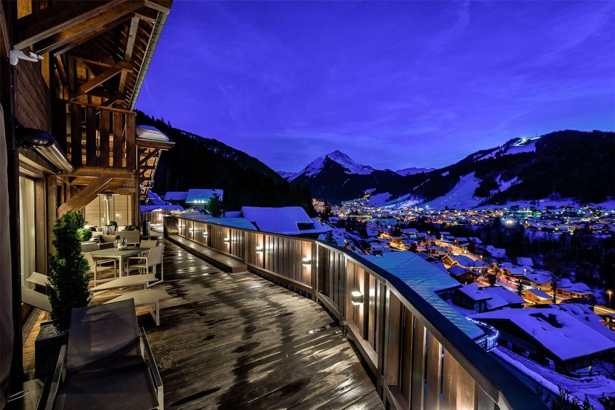A balcony overlooking a snowy mountain town at night