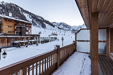 A bathroom with a sink and a mirror with a balcony in the background