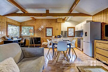 A living room with a couch a table and chairs and a refrigerator from mountain base immobilier real estate