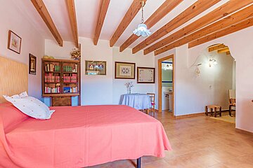 A bedroom with a bed and a bookshelf with books on it