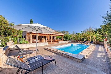 A large swimming pool is surrounded by chairs and an umbrella