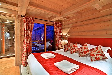 A bedroom with a large bed and red pillows