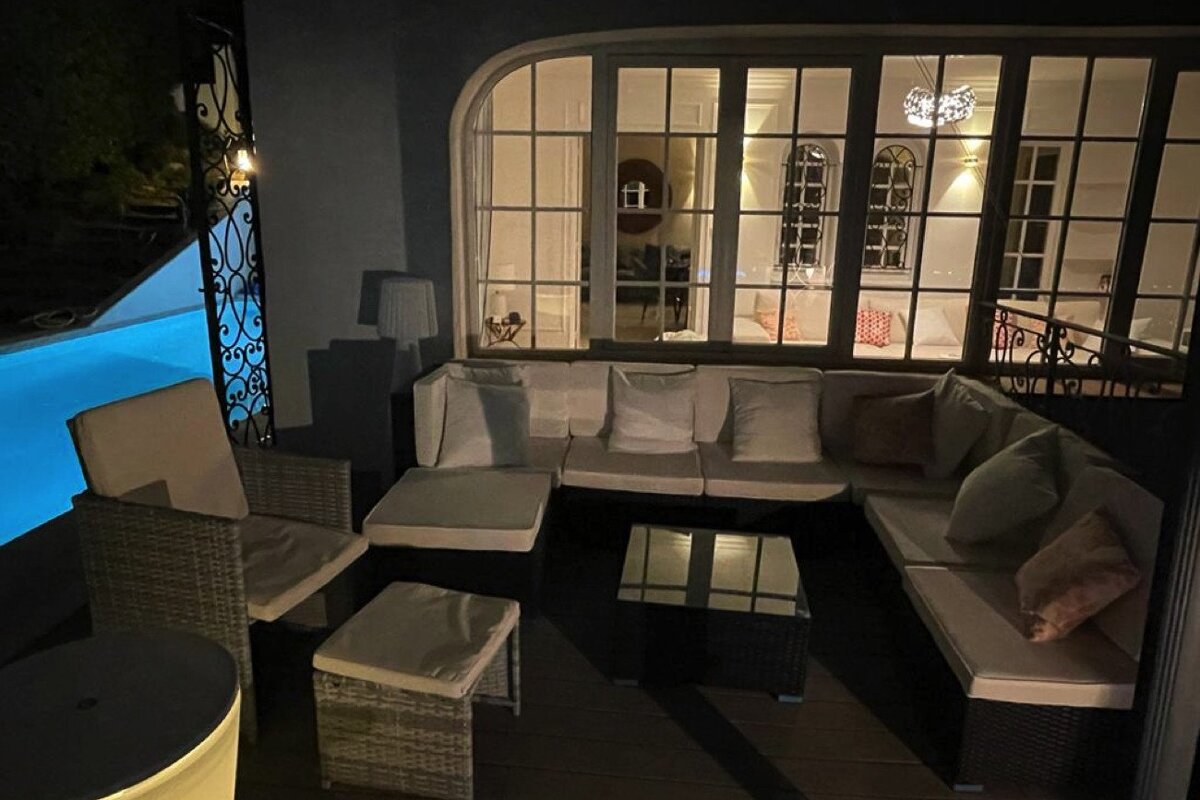 A patio with wicker furniture and a swimming pool in the background