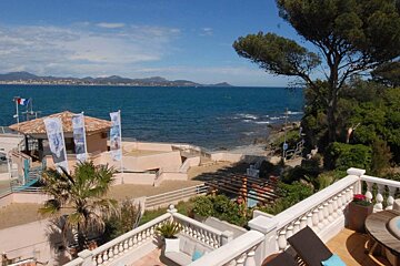 A view of the ocean from a balcony with a few flags on it