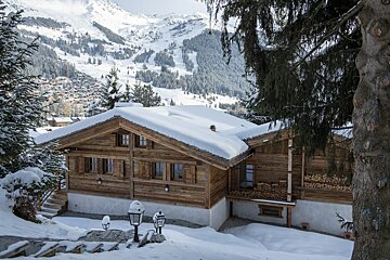 A snowy mountain landscape with a wooden house in the foreground