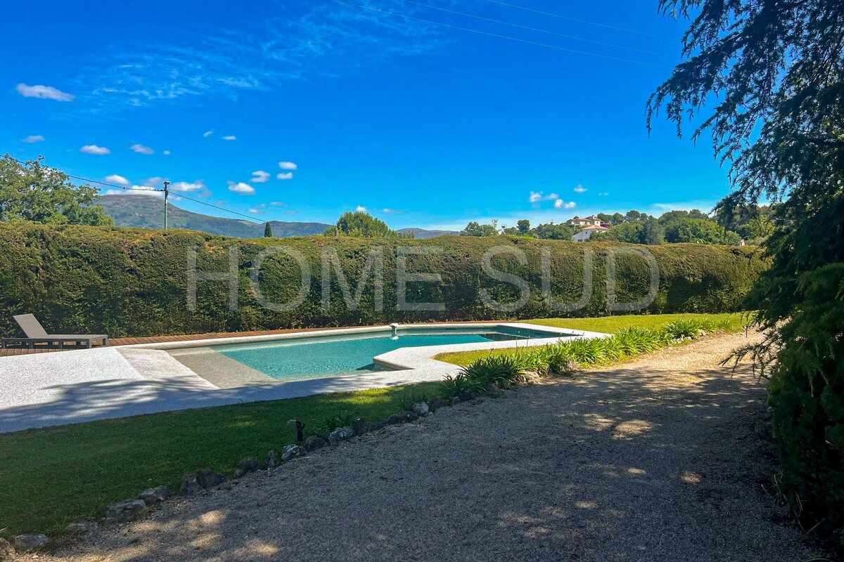 A large swimming pool is surrounded by a lush green hedge with the words home sud written on it