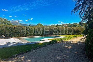 A large swimming pool is surrounded by a lush green hedge with the words home sud written on it